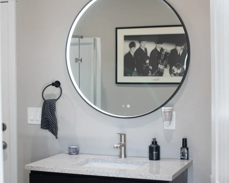 Bathroom off the bonus room with a backlit round mirror over the vanity