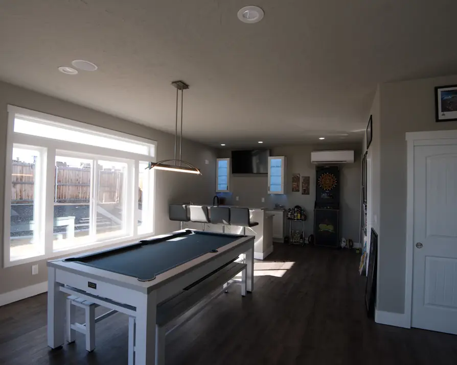 Finished bonus room: recessed lights, a linear pendant over a pool table, lit glass cabinets and a wall TV
