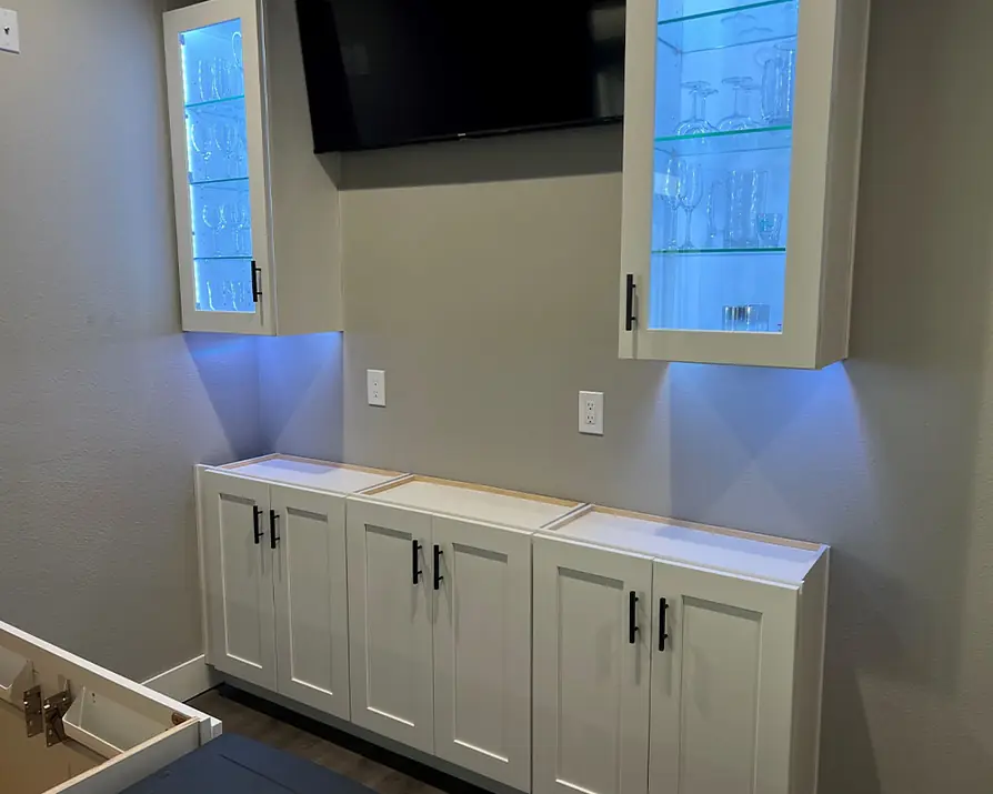 White bar cabinets with lit glass uppers and a blue glow underneath