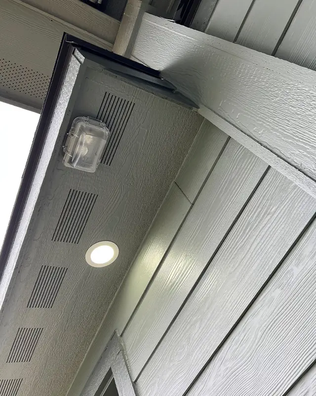 A soffit can light and a jelly-jar fixture under the eaves seen from below