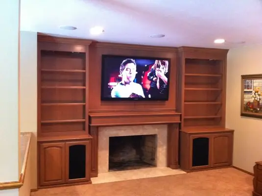 A wall TV set into built-in cabinetry over a fireplace